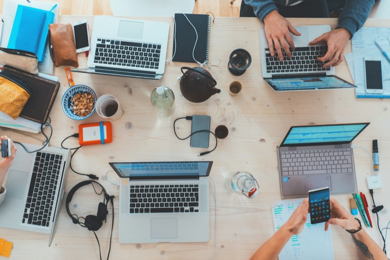 A desk from above, covered with laptops and planning notes